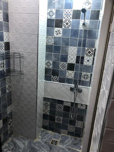 y baño con ducha y azulejos azules y blancos. en Chez ZAKARIA de Lyon, en Meknès