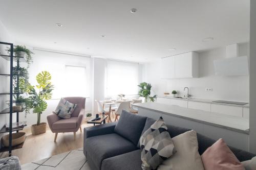 een woonkamer met een bank en een keuken bij Lujoso apartamento entre 2 playas con garaje in Gijón