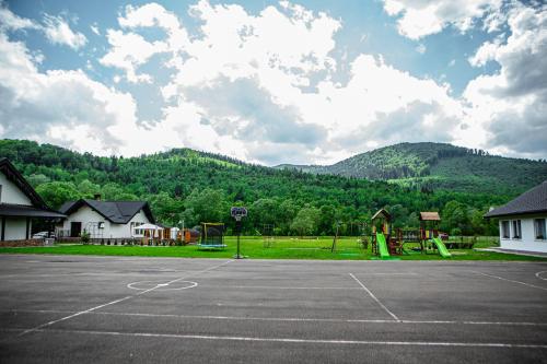 an empty parking lot with a playground in front of a mountain at Pensiunea ARC Bucovina in Vama