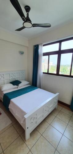 a bedroom with a white bed and a window at Penthouse Five - The Beautiful 3Br En-suite Apt in Mombasa