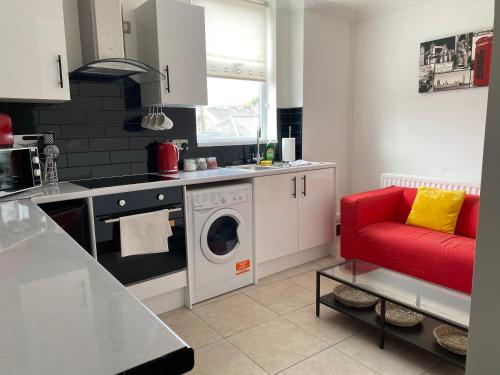 a kitchen with a washing machine and a red couch at Modern 2 Bedroom Flat in Robert st Swansea in Swansea