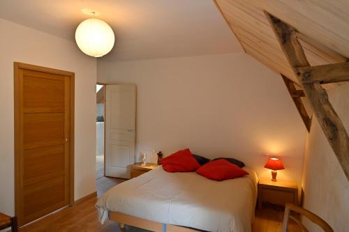 - une chambre avec un lit doté d'oreillers rouges dans l'établissement LES CHAMBRES AUX LOUPS, à Iffendic