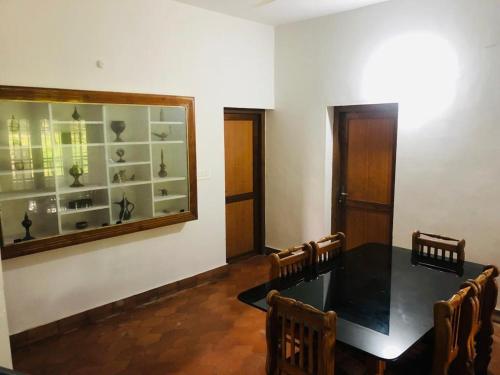 a dining room with a table and chairs and a mirror at H Villa in Nilambūr