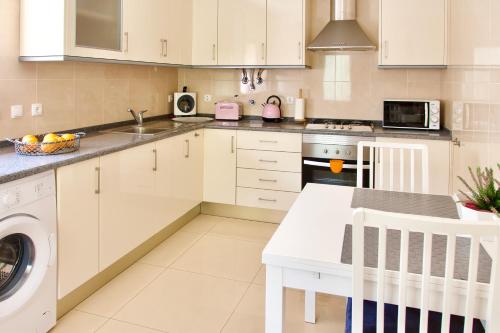 a kitchen with white cabinets and a sink and a dishwasher at Edificio Tomás 1 in Ferragudo