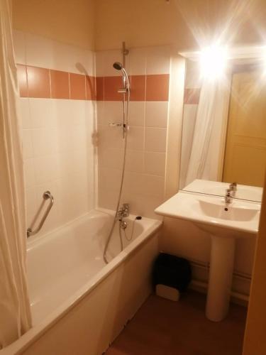 La salle de bains est pourvue d'une baignoire, d'un lavabo et d'une douche. dans l'établissement Appartement de standing - La Bourboule, à La Bourboule