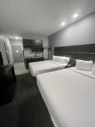 a hotel room with two beds and a kitchen at Days Inn by Wyndham Zachary LA in Zachary