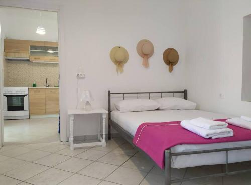 een witte slaapkamer met 2 bedden en een keuken bij Το σπίτι της Μαργαρίτας στην παραλία in Nea Stira