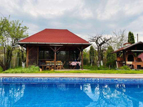 a gazebo and a swimming pool in front of a house at Pensiunea Enothera in Văleni- Dîmboviţa