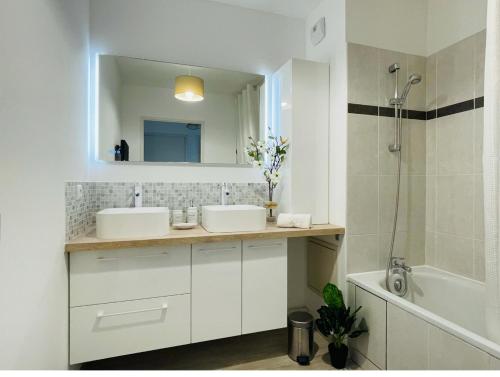 La salle de bains est pourvue de 2 lavabos, d'un miroir et d'une baignoire. dans l'établissement Joli appartement Proche Disney, à Chanteloup-en-Brie