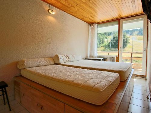 a bedroom with two beds and a large window at Appartement Chamrousse, 2 pièces, 4 personnes - FR-1-549-69 in Chamrousse