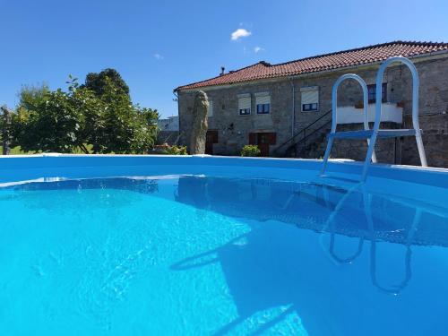 a blue swimming pool with a chair in the water at Quinta da Ponte in Viana do Castelo