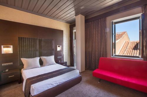 a bedroom with a large bed and a red couch at Aion Luxury Hotel in Nafplio