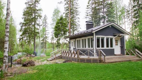 ein winziges Haus im Wald mit einer Terrasse in der Unterkunft Venejoen Piilo - Kuohu in Kontiolahti