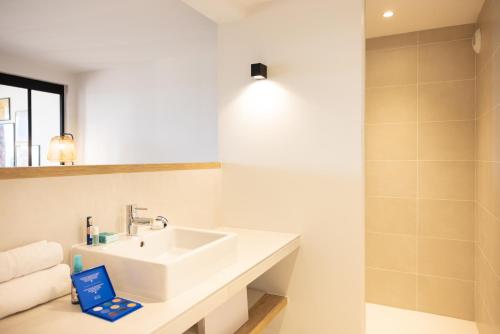 a white bathroom with a sink and a mirror at La Bergerie Yves Rocher in La Gacilly