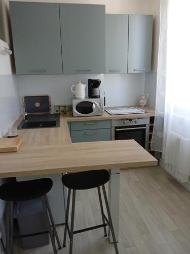 a kitchen with a counter and two bar stools at Aux prés verts in Fécamp