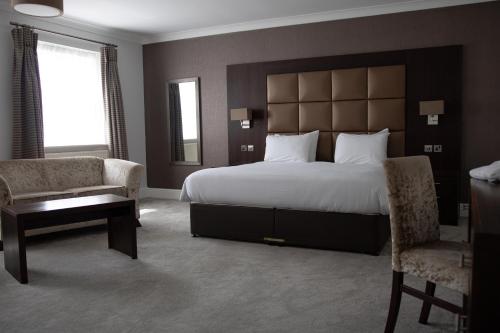 a bedroom with a large bed and a desk and chair at Lion Hotel in Worksop