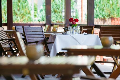 a table with a white table cloth and red flowers on it at Pension Pantheon in Poiana Brasov