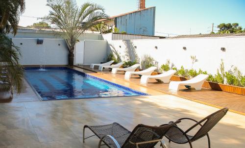 a swimming pool with chairs next to a building at Rede Andrade Vivaldi in Foz do Iguaçu