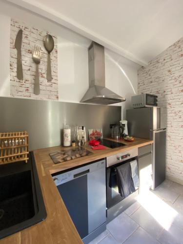 uma cozinha com um lavatório e uma bancada em Logement avec jardin privé confortablement équipé em Bagard