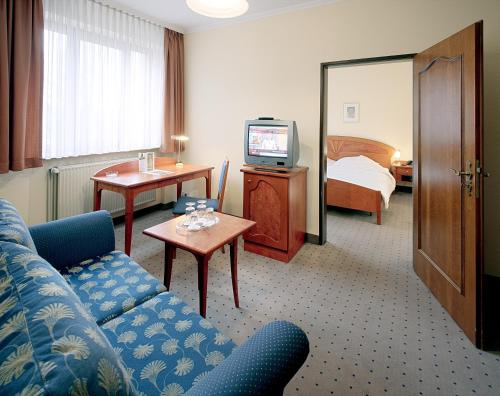 a hotel room with a couch and a television at Tryp by Wyndham Kassel City Centre in Kassel