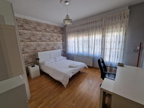 1 dormitorio con cama blanca, escritorio y ventana en Apartamento ideal Florida, en Vitoria-Gasteiz