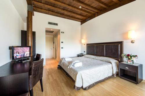 a bedroom with a bed and a desk with a television at Hotel Smeraldo in Lignano Sabbiadoro