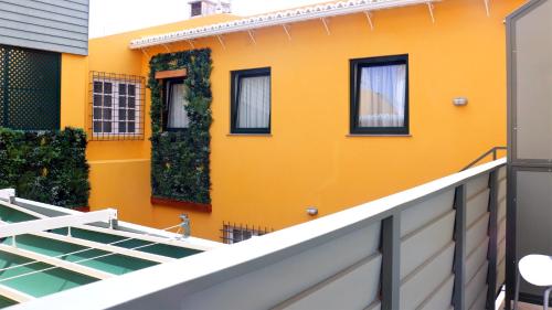 a yellow house with windows and a balcony at Aliança café & hostel in Angra do Heroísmo
