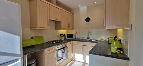 a kitchen with white cabinets and green accents at The Honeypot - Cornish Apartment close to Eden Project & beaches in Par