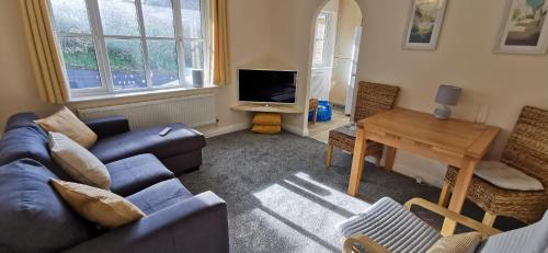 a living room with a blue couch and a table at The Honeypot - Cornish Apartment close to Eden Project & beaches in Par