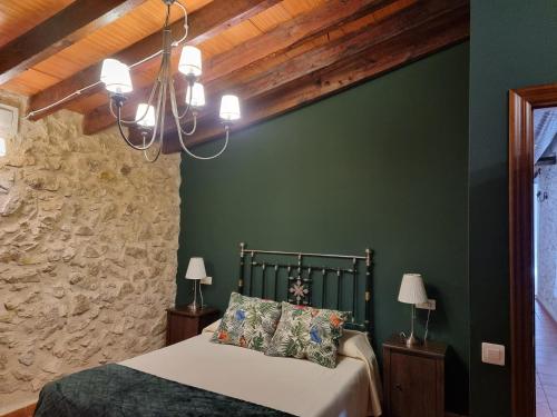 ein Schlafzimmer mit grünen Wänden, einem Bett und einem Kronleuchter in der Unterkunft Apartamentos rurales La Alquería del Pilar in Banyeres de Mariola