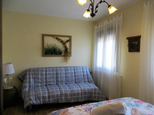 a bedroom with a blue couch and a window at Casa Rural El Remolón in Piñuécar