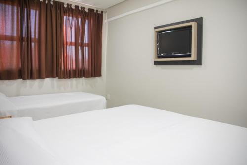 a room with two beds and a flat screen tv at Rede Andrade Vivaldi in Foz do Iguaçu