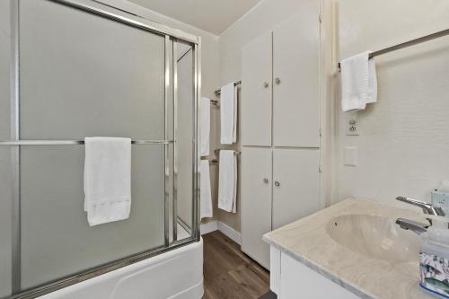 a white bathroom with a shower and a sink at Sandy Feet Retreat -- Lakefront Retreat With Sand Volleyball Court! in Clearlake Oaks