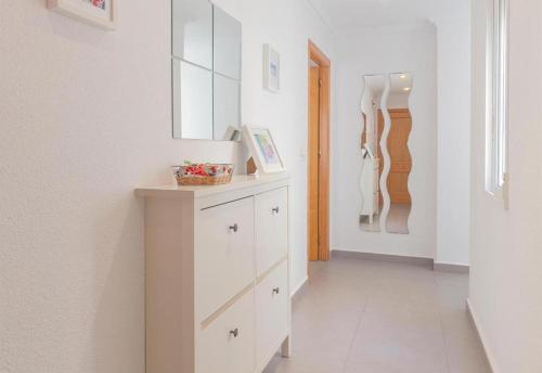 una cucina bianca con armadio e specchio di Seaview modern beach apartment a Guardamar del Segura