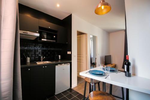 une cuisine avec des armoires noires et un comptoir blanc dans l'établissement Le Bois, T2 hypercentre chic et cosy, Wifi par SOVALFI, à Saint-Étienne