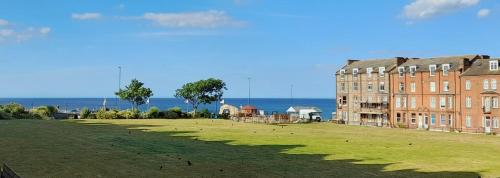 um grande campo relvado ao lado de um grande edifício de tijolos em Driftwood Studio em Cromer