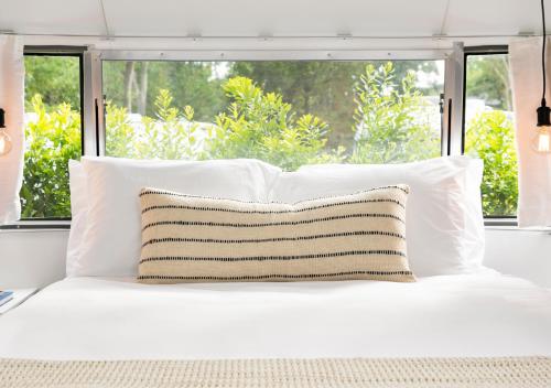 a white bed with white pillows and a window at AutoCamp Cape Cod in Falmouth