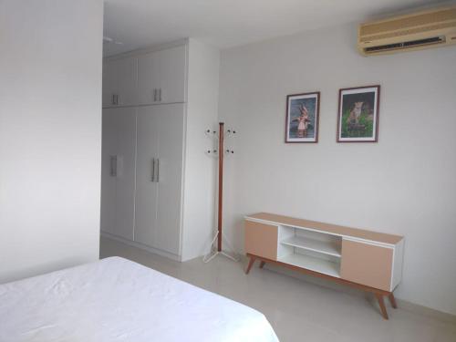 a white bedroom with a bed and a dresser at Excelente Flat no Centro de Manaus próximo ao Teatro Amazonas. in Manaus