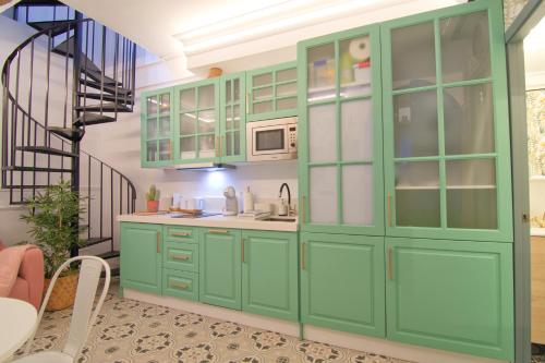 eine Küche mit grünen Schränken und einer Wendeltreppe in der Unterkunft Mara's Apartments Torremolinos LA MAR -Little House - First Line Beach - Bajondillo in Torremolinos