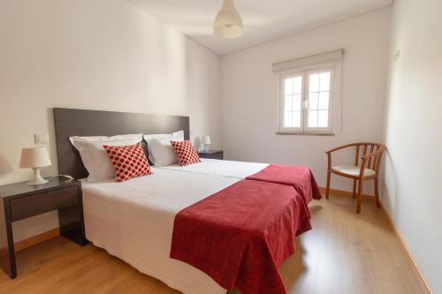 テルマス・デ・サン・ペードロ・ド・スルにあるCasa Cimo de Vilaのベッドルーム1室(赤い枕と椅子付きのベッド1台付)