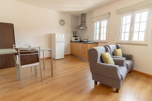 a living room with a table and a chair and a kitchen at Casa Cimo de Vila in Termas de Sao Pedro do Sul