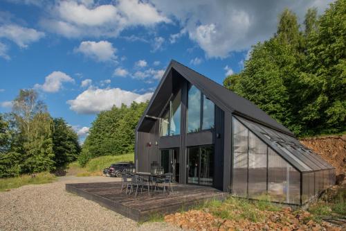 una casa negra con puertas de cristal y una mesa en Czarny domek w górach, en Pieszyce