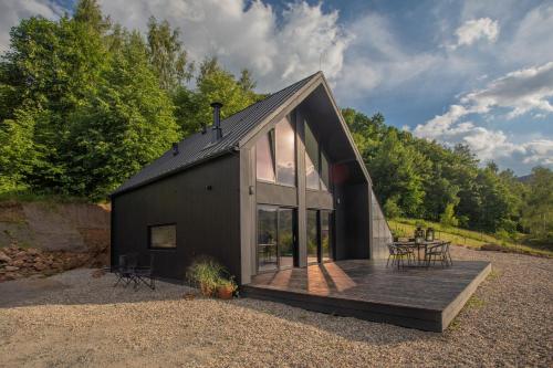 a black house with a deck and some trees at Czarny domek w górach in Pieszyce