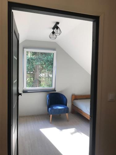 a room with a blue chair and a window at Leśny Domek in Czerwona Wola