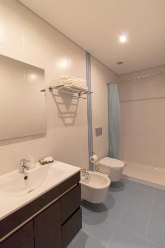 a bathroom with a sink and a toilet and a mirror at Casa Cimo de Vila in Termas de Sao Pedro do Sul