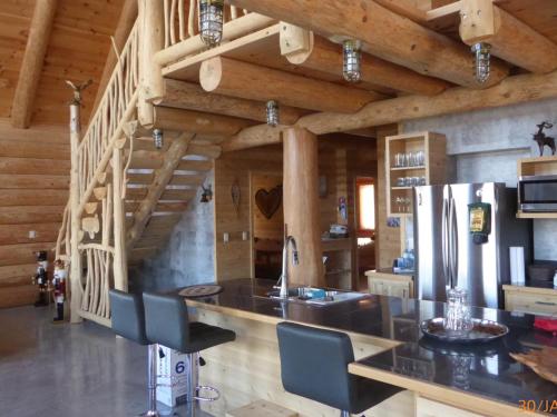 a kitchen with a counter with chairs and a refrigerator at B&B Le Chalet Bois de Coeur in Saint Come