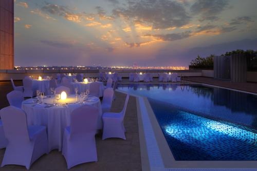 a restaurant with white tables and chairs next to a pool at Millennium Central Downtown in Dubai