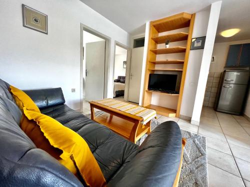 een woonkamer met een leren bank en een tafel bij Apartments Lokunja in Pag