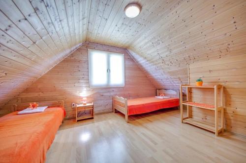Cette chambre mansardée comprend 2 lits et une fenêtre. dans l'établissement Zagroda Bukowiec, à Polańczyk