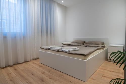 a white bedroom with a bed and a window at Beautiful modern apartment with large livingroom in Bihać